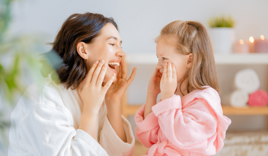Woman Looking After A Child's Skin Laughing And Putting Facecream On