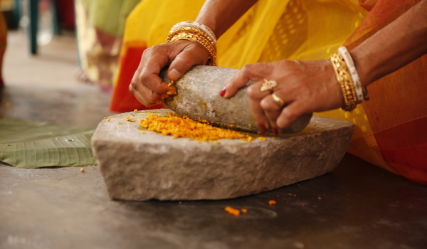 Woman In India Crushing Turmeric For Beauty Routine