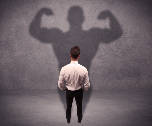 Small business owner standing in front of an oversized, powerful shadow, representing the pressure to look successful in business.